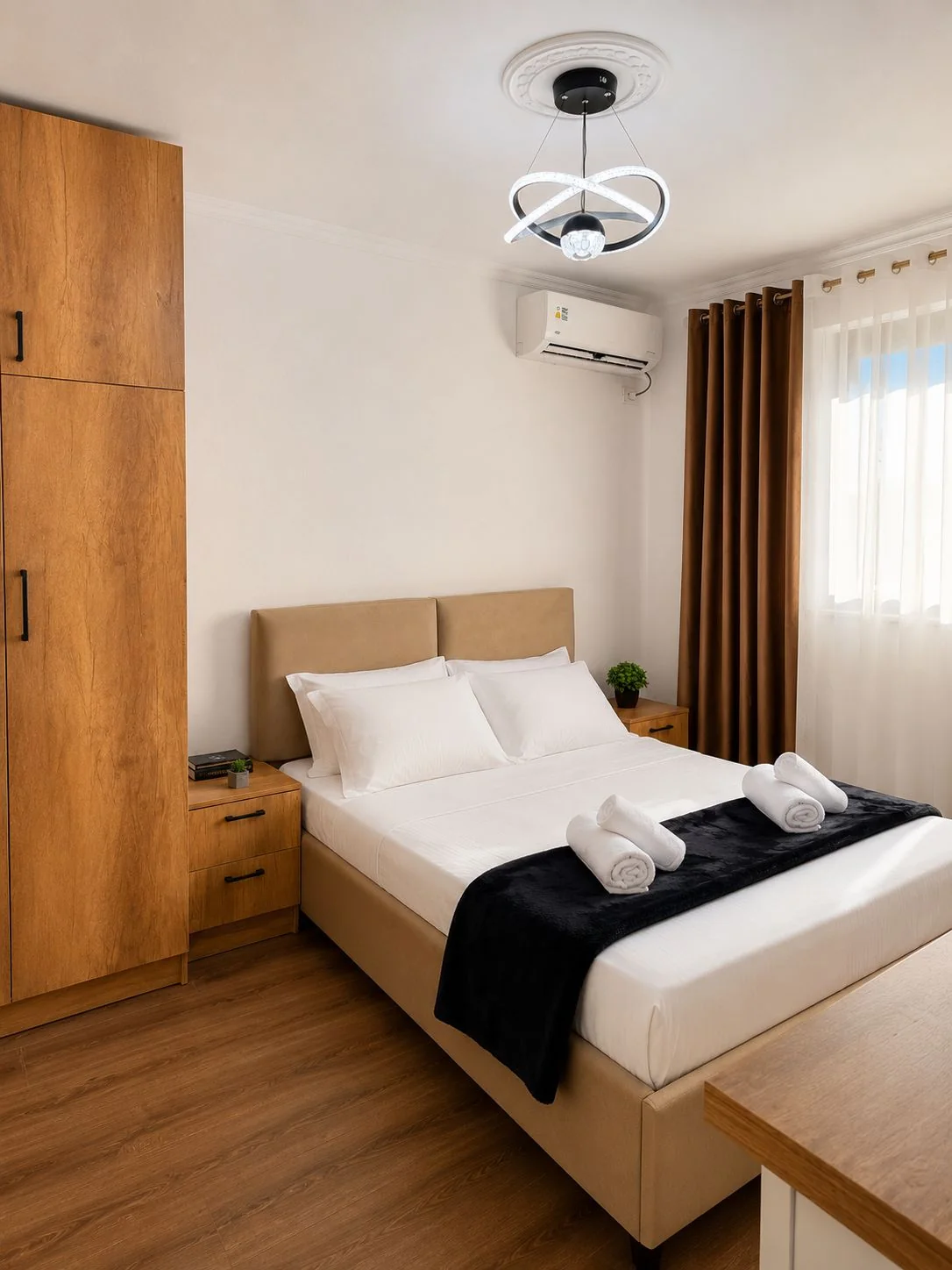 Bedroom at Olen's Apartments in Tirana with a double bed, white bedding, wooden wardrobe and air conditioning